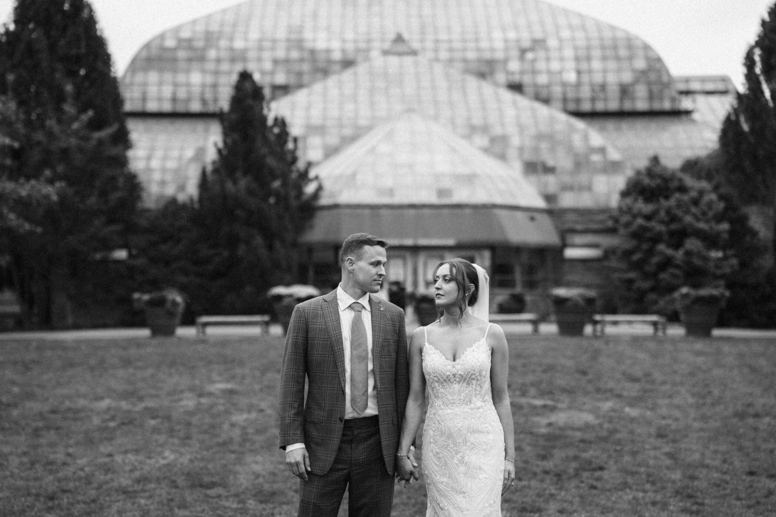 Bride and groom holding hands during a Chicago elopement in Lincoln Park, photographed in front of the Lincoln Park Conservatory on a late October wedding day.