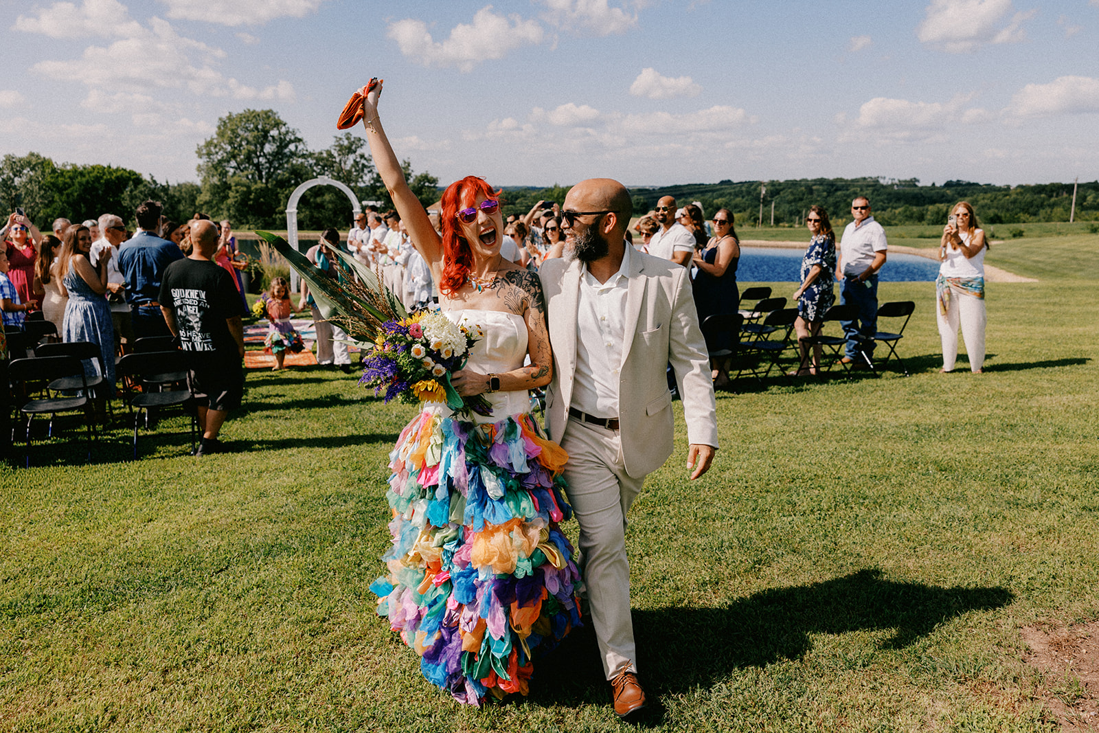 husband and wife hold hands and celebrate after their ceremony, dressed in vibrant colors.